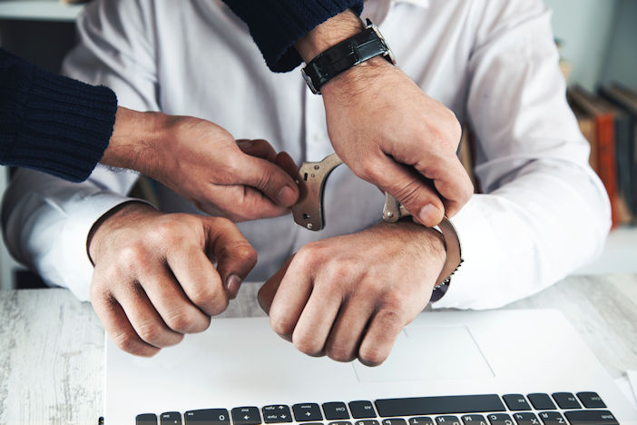 Someone being handcuffed while on the computer.