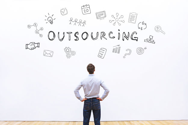 A man staring at a white wall that saying "outsourcing" with related doodles floating around the lettering.